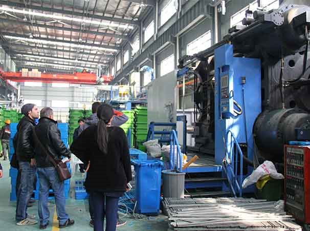 Customer delegation inspecting a large injection molding machine with XDPC staff